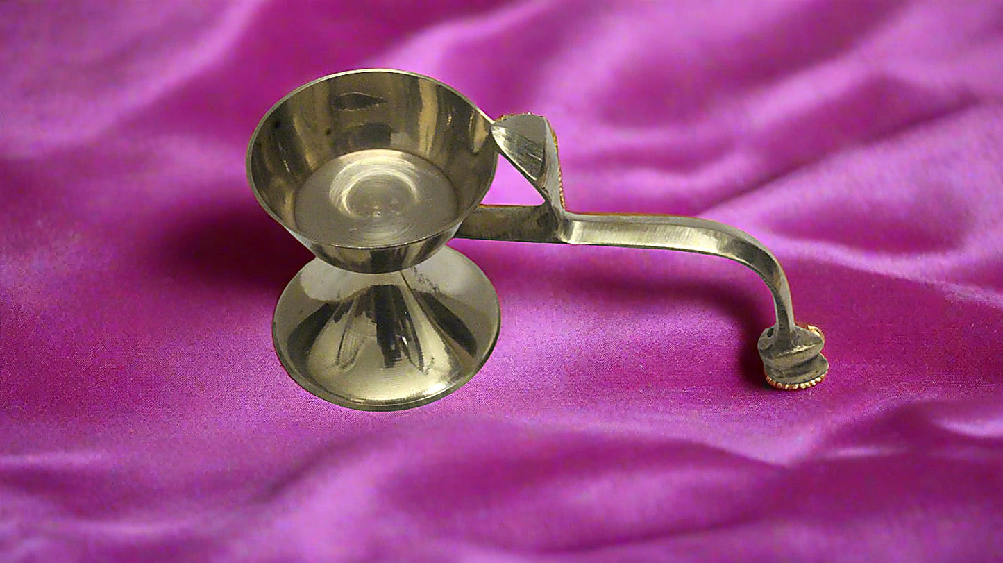 Brass oil lamp on a purple fabric background