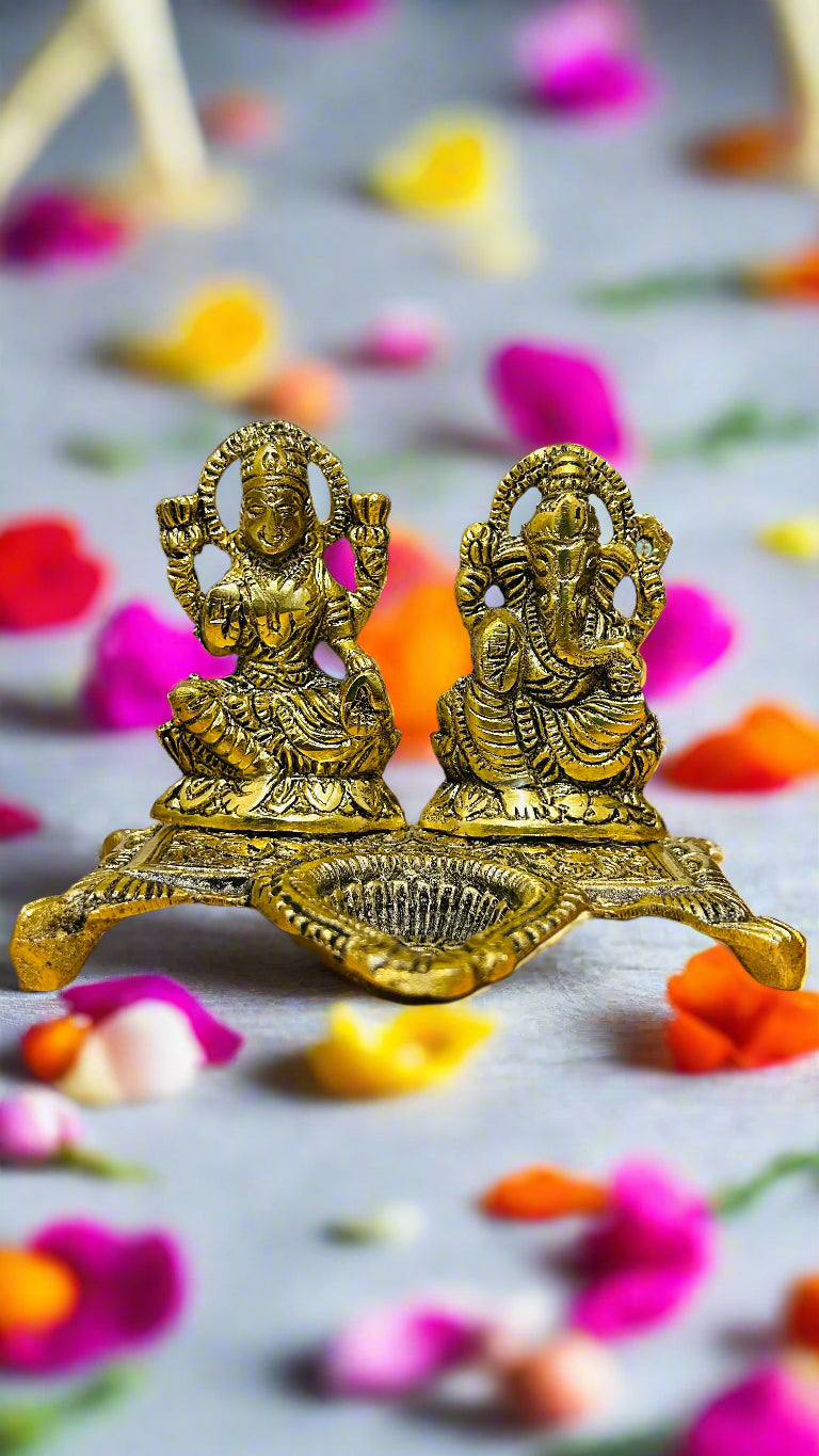 Gold-colored deity statues on a surface with colorful flower petals
