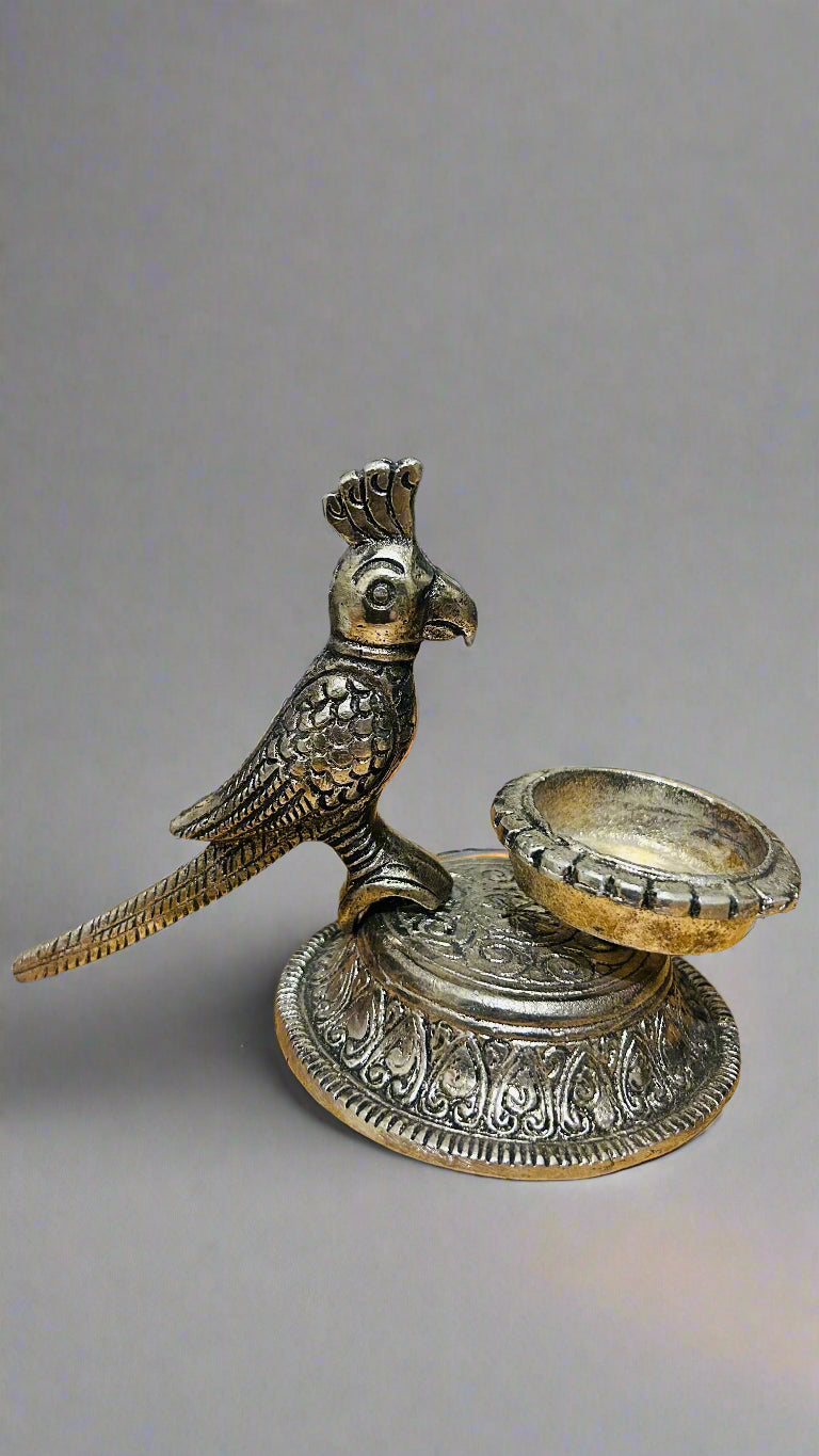 Decorative metal bird-shaped candle holder on a wooden surface