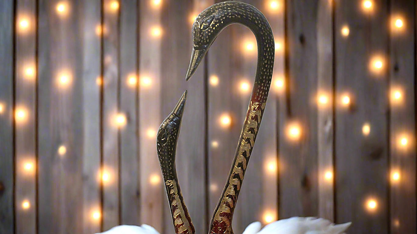 Decorative swan sculpture against a wooden background with string lights