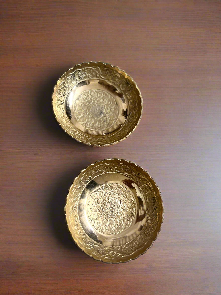 Two gold decorative plates on a textured surface with a blue and white background