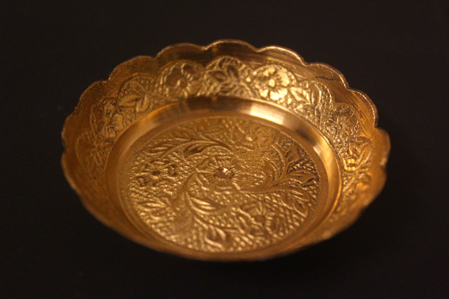 Gold decorative bowl with intricate patterns on a black background