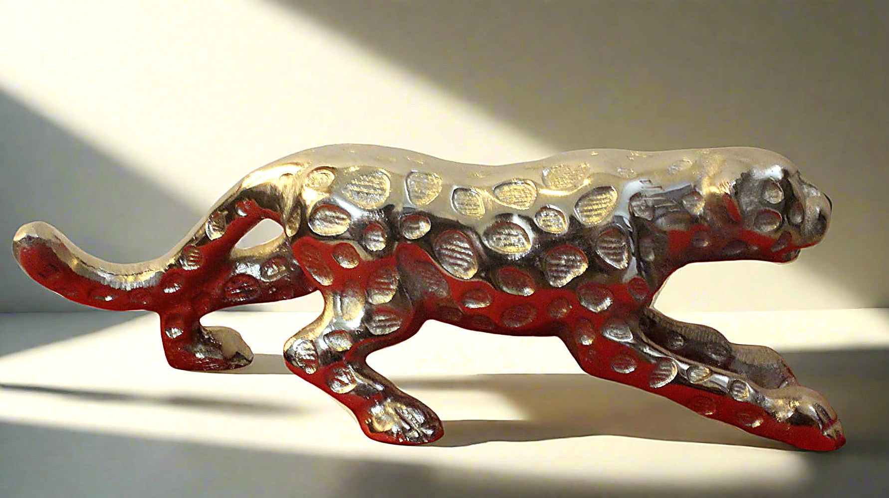 Decorative figurine of a panther with red and silver design on a white background