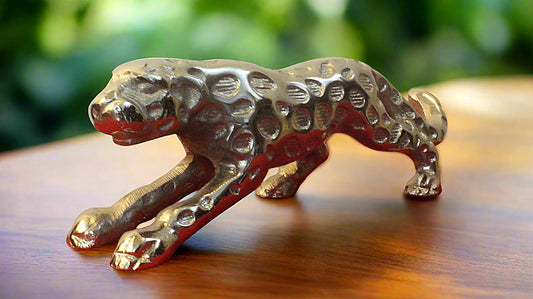 Gold tiger figurine on a wooden surface with a blurred green background