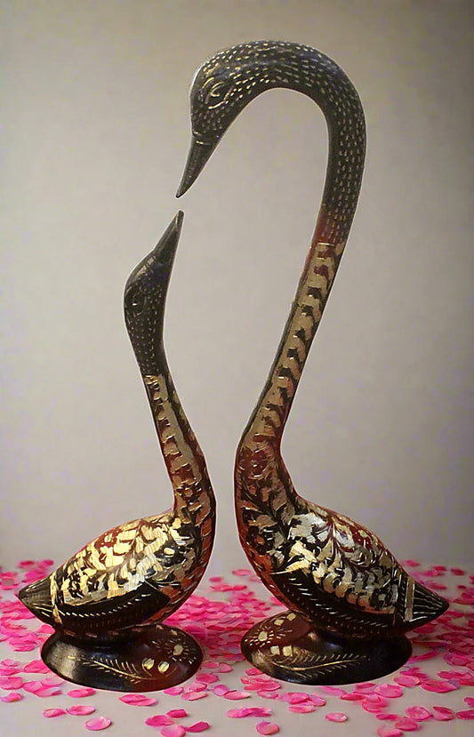 Decorative brass swans on a pink and white background