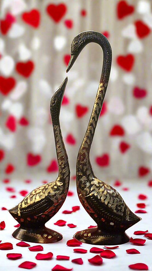 Bronze swan statues with a heart-themed background