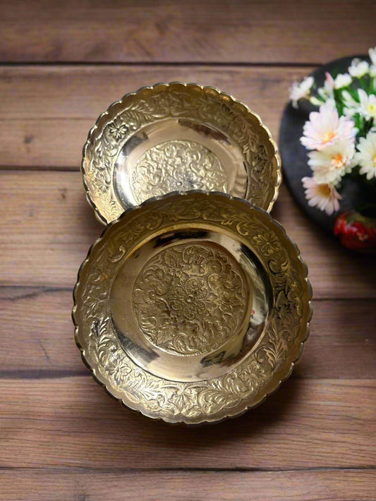 Two ornate silver trays with intricate designs on a patterned surface.