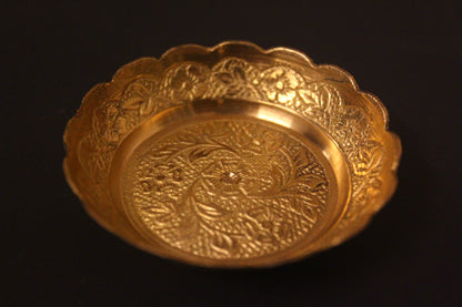 Gold decorative bowl with intricate patterns on a black background