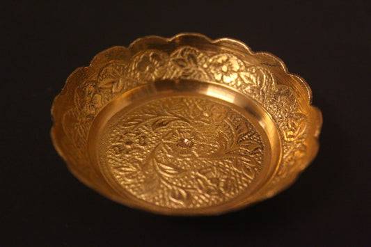 Gold decorative bowl with intricate patterns on a black background
